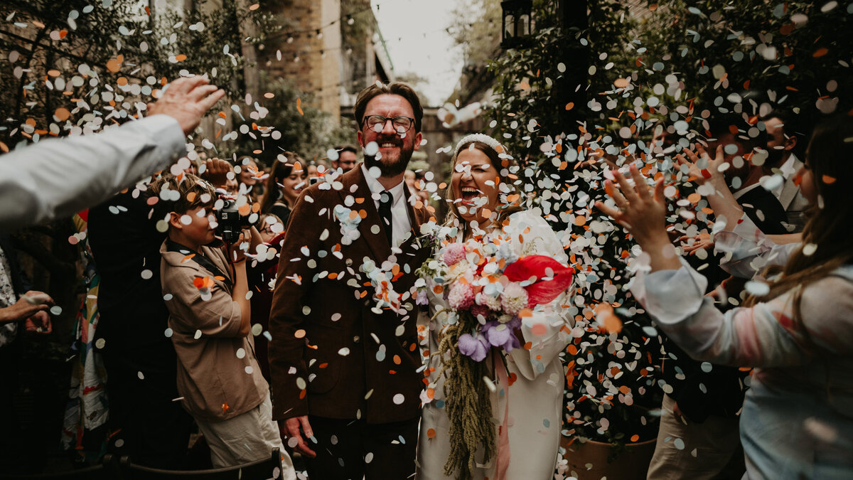 Bride and groom make their way back up the aisle at 100 Barrington in London as their wedding guests throw confetti. 