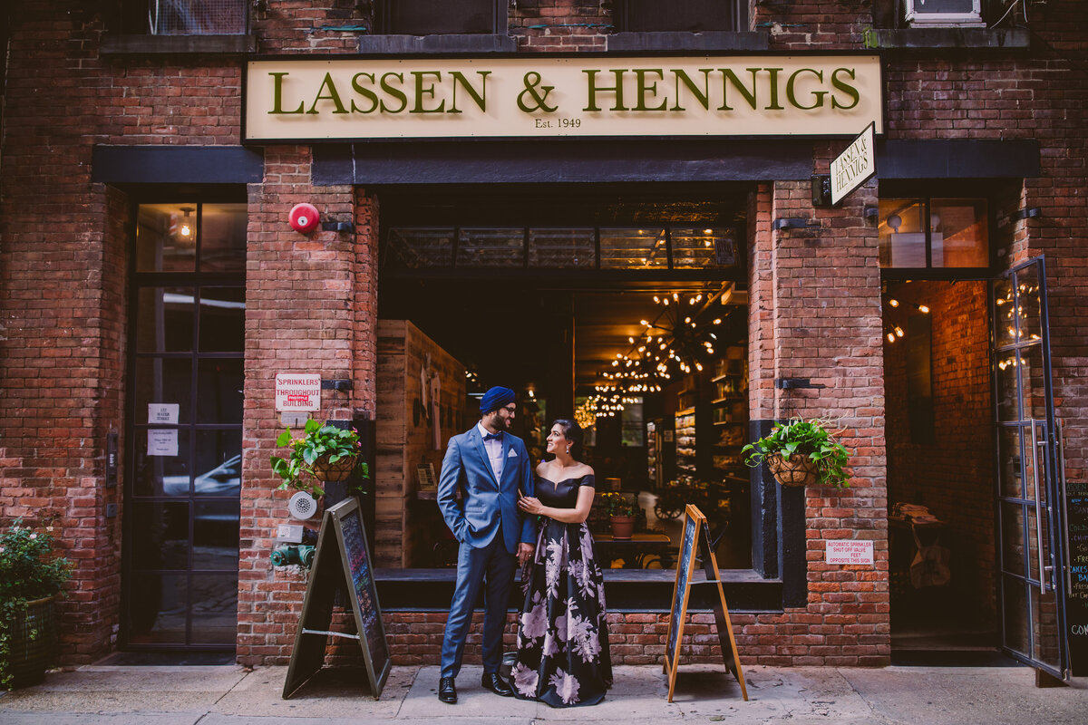An engagement couple in formal clothing standing outside the lassen & hennigs store in brooklyn new york in dumbo