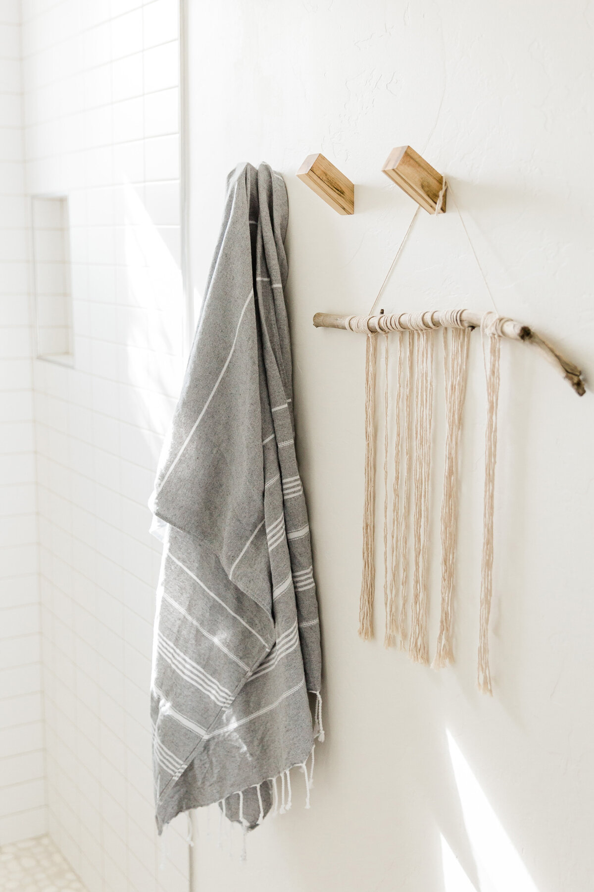 white bathroom wall with lienen towel on natural wood hooks