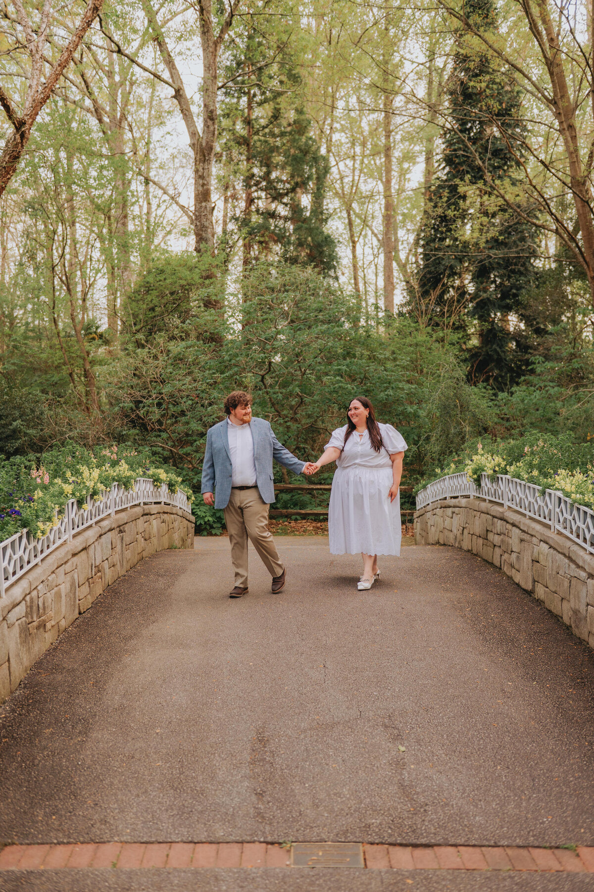 A couple holds hands while walking on a bridge