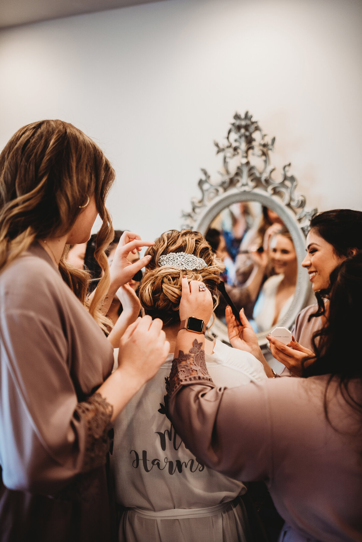 a bride surrounded by her bridesmaids fussing about her on her wedding day