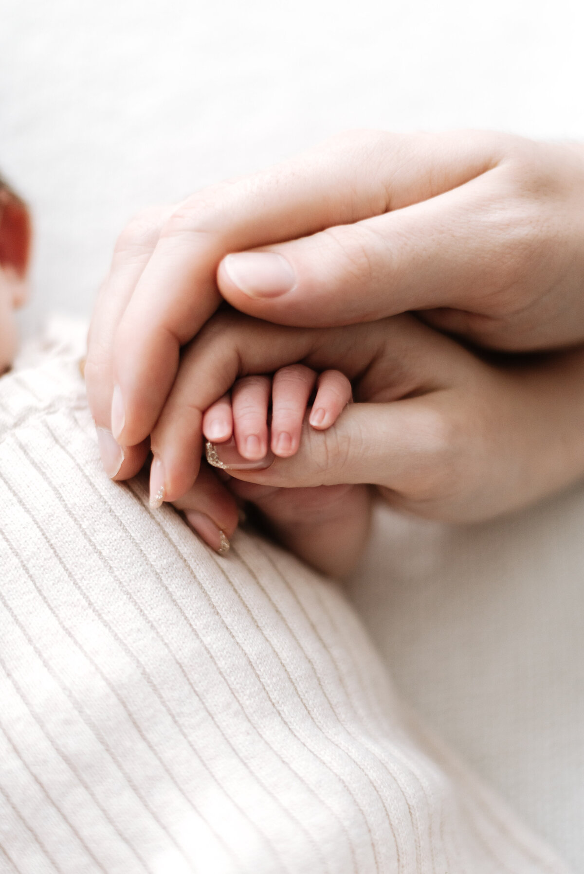 Photo of mum and dads hands holding their newborn babies hands at Billingshurst newborn photography