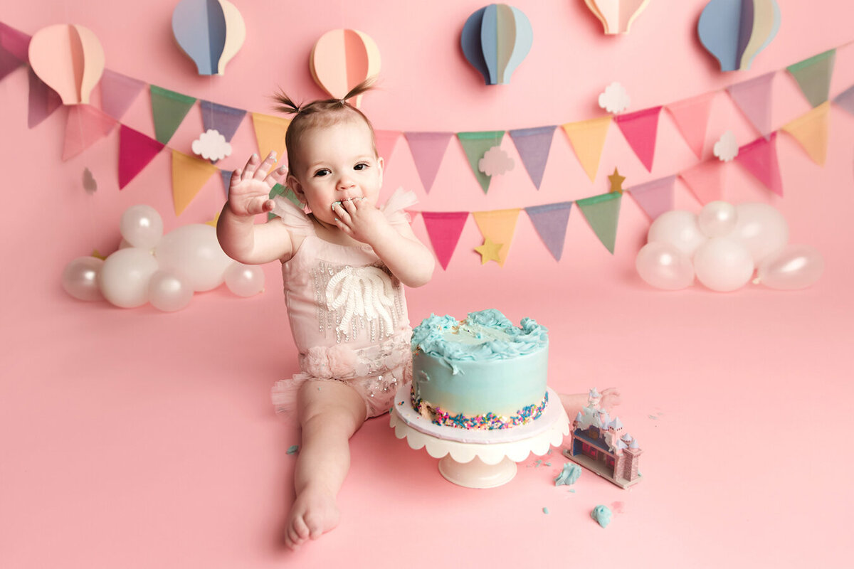 Adorable baby girl with pink and disney theme decor celebrating first birthday