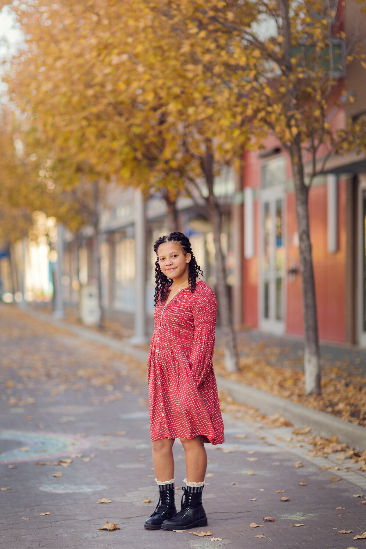 Tween girl in red dress and boots in the fall at a mini session.