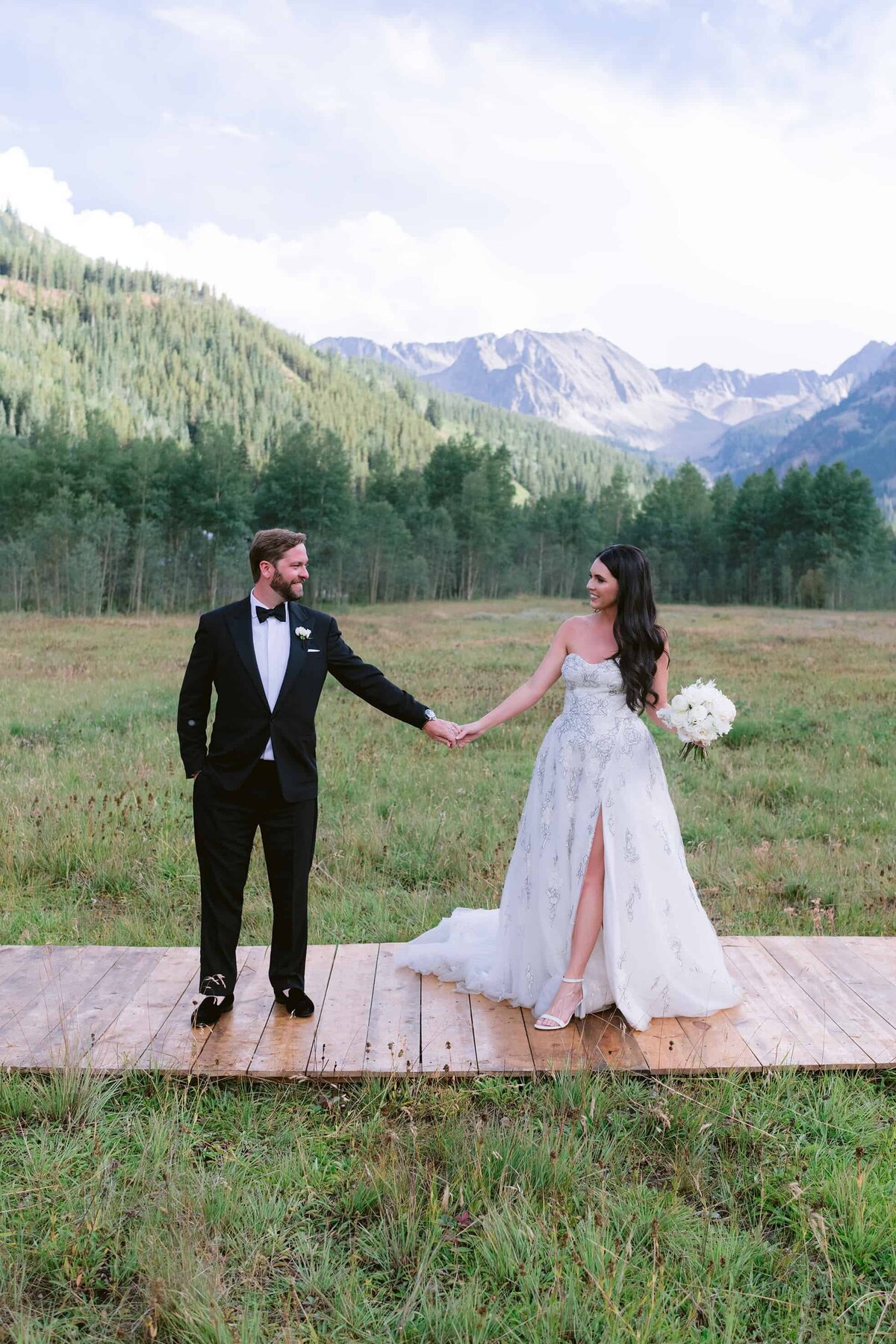 Bride and groom holding hands in front of mountains