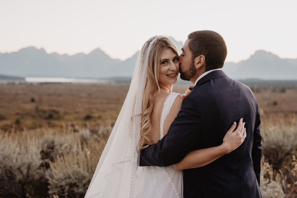 Photographers Jackson Hole capture groom kissing bride's cheek