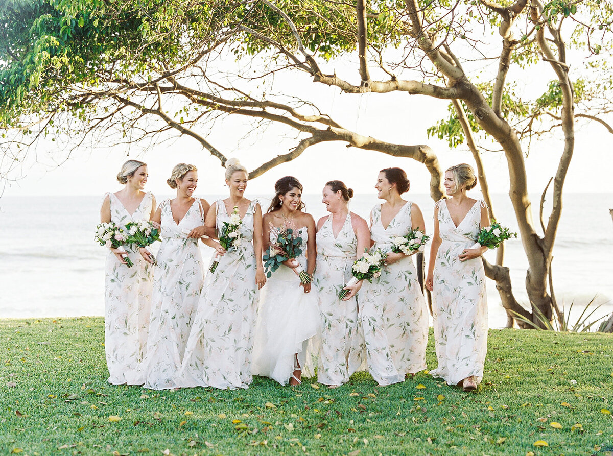a bride standing with her bridesmaids, all in white dresses