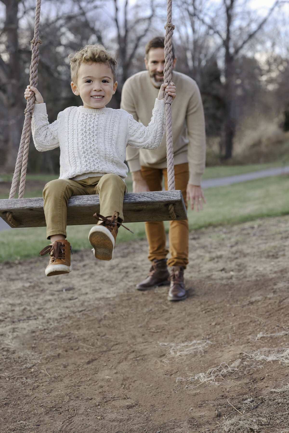 Dad pushing boy on swing when they visit Asheville