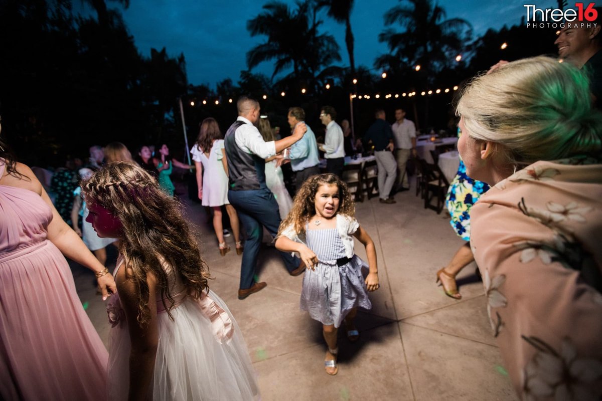 Little girl dances in the middle of the dance floor at wedding reception