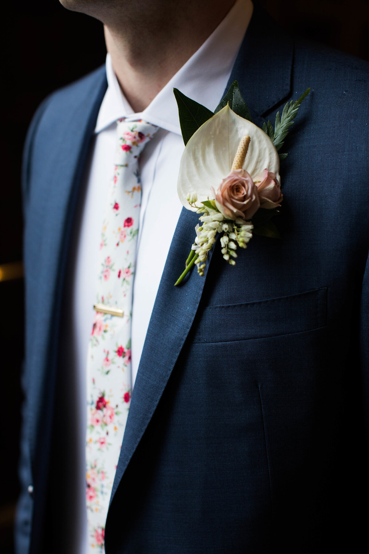 Groom in navy suit with floral tie and boutonniere