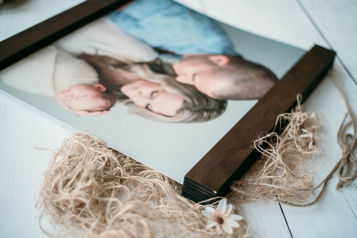 Hanging wall art encased in wood with family newborn portrait on it