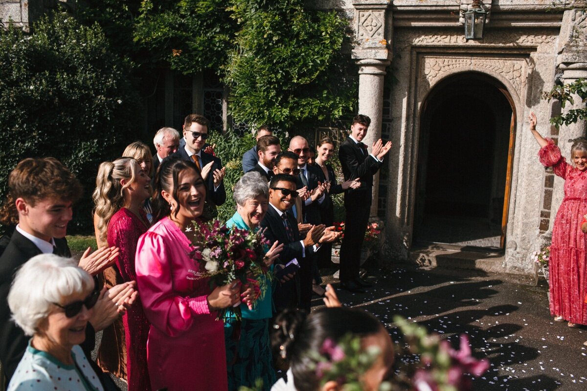 A sea of happy faces look on towards their freidn who are newlyweds
