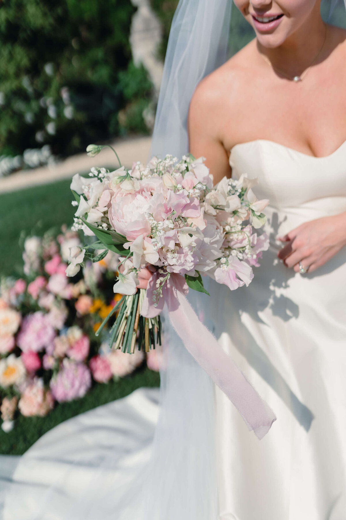 closeup of a bride leaving her summer garden wedding ceremony holding a bouquet of pink and white flowers at romantic cotswold venue euridge manor