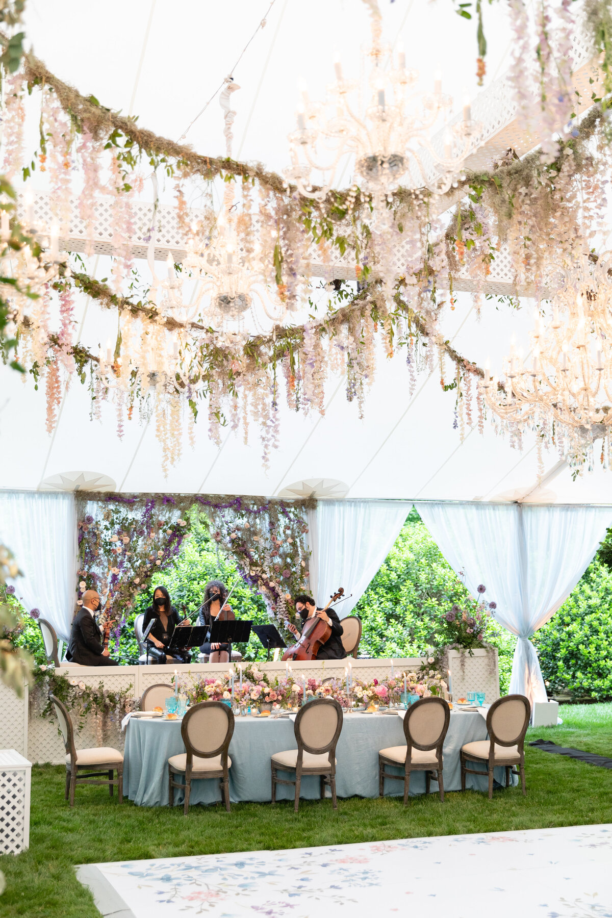 Growing, fresh floral installations with blush garden roses, lavender delphinium, wisteria, globe allium, and vines and greenery for a tented Bridgerton inspired engagement party at a private home in Nashville, TN. Flower by Tennessee based wedding f