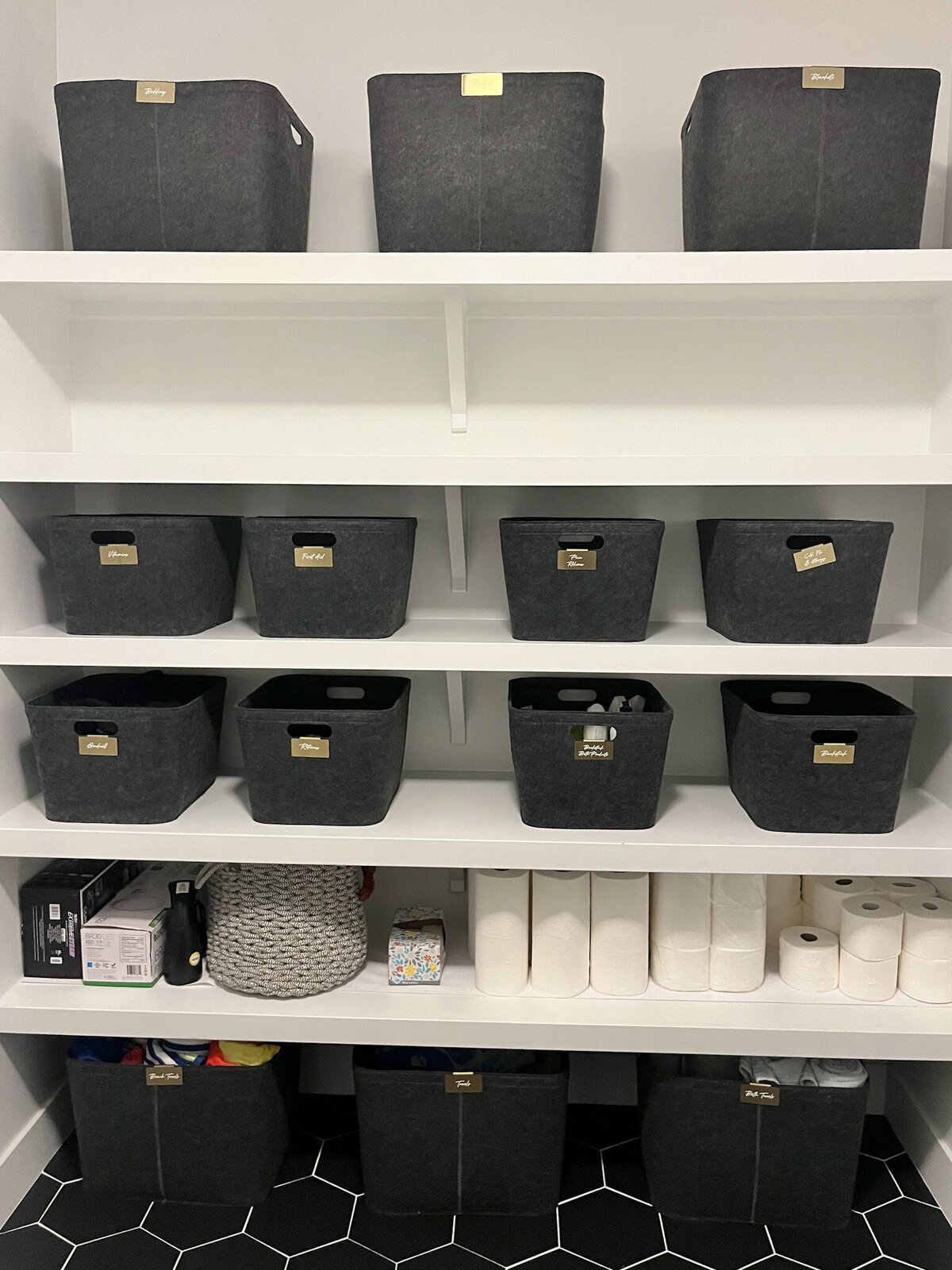 linen closet with black fabric baskets on shelves