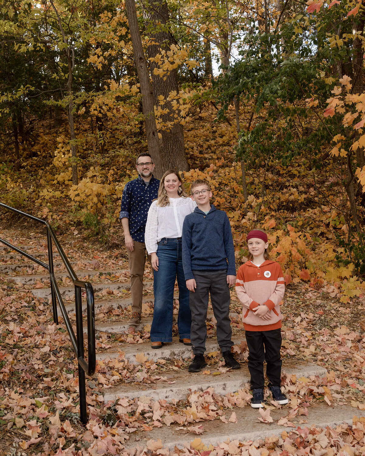 Family of 4 standing on different steps on a fall evening.