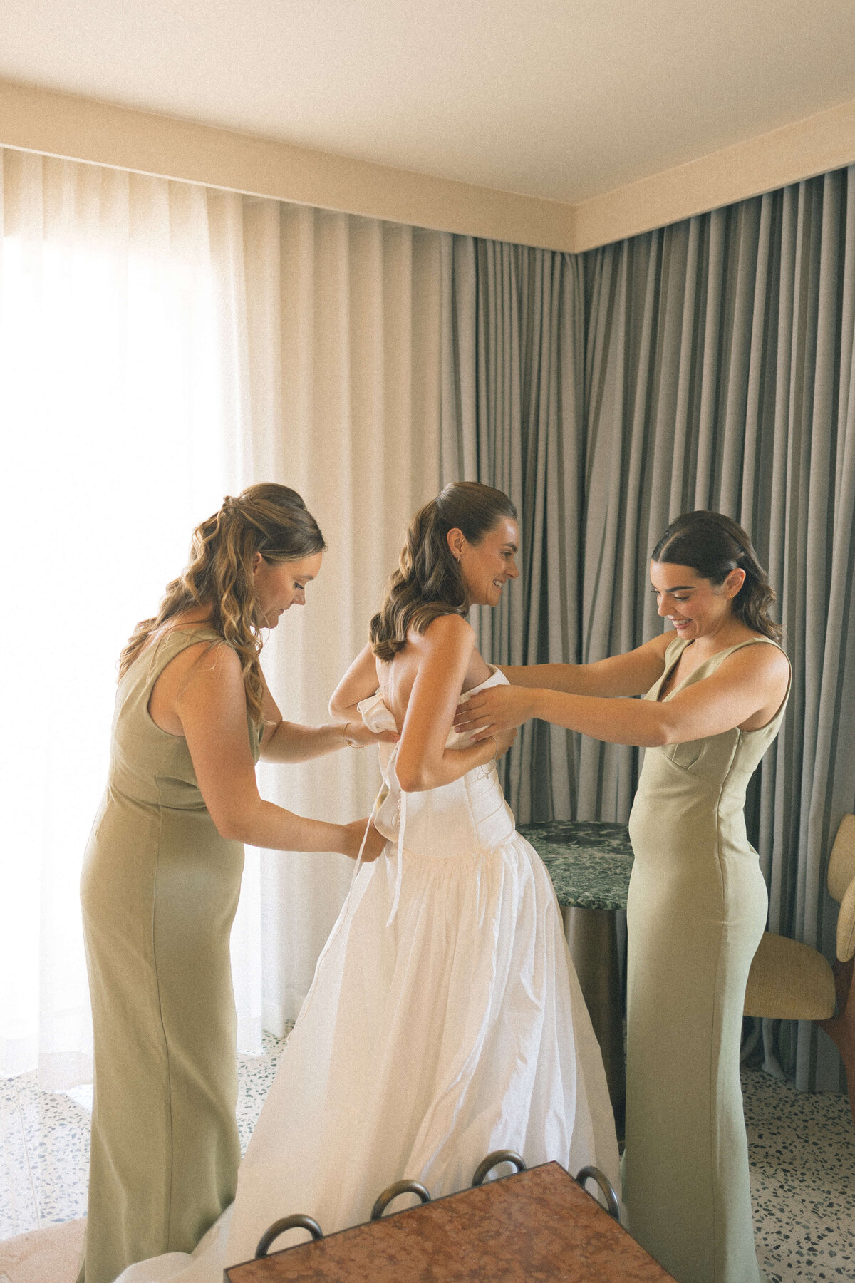 Bridesmaid helping bride into dress at Soho House Rome suite