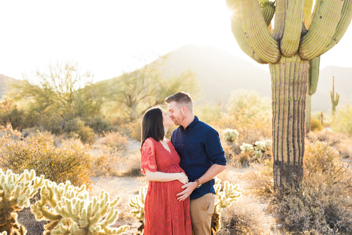 mom and dad to be kissing and holding bump