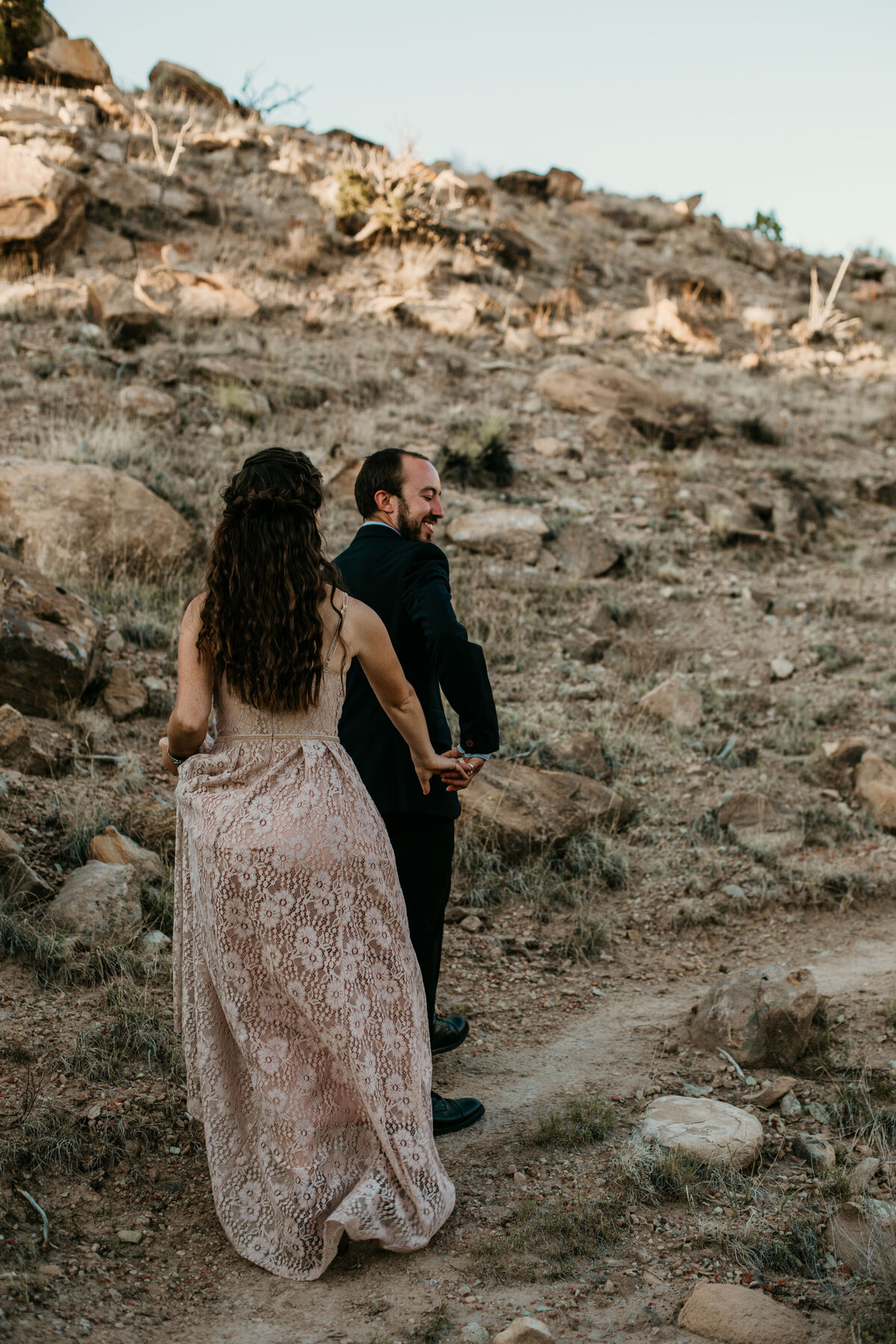 groom leading bride up a trail in the desert