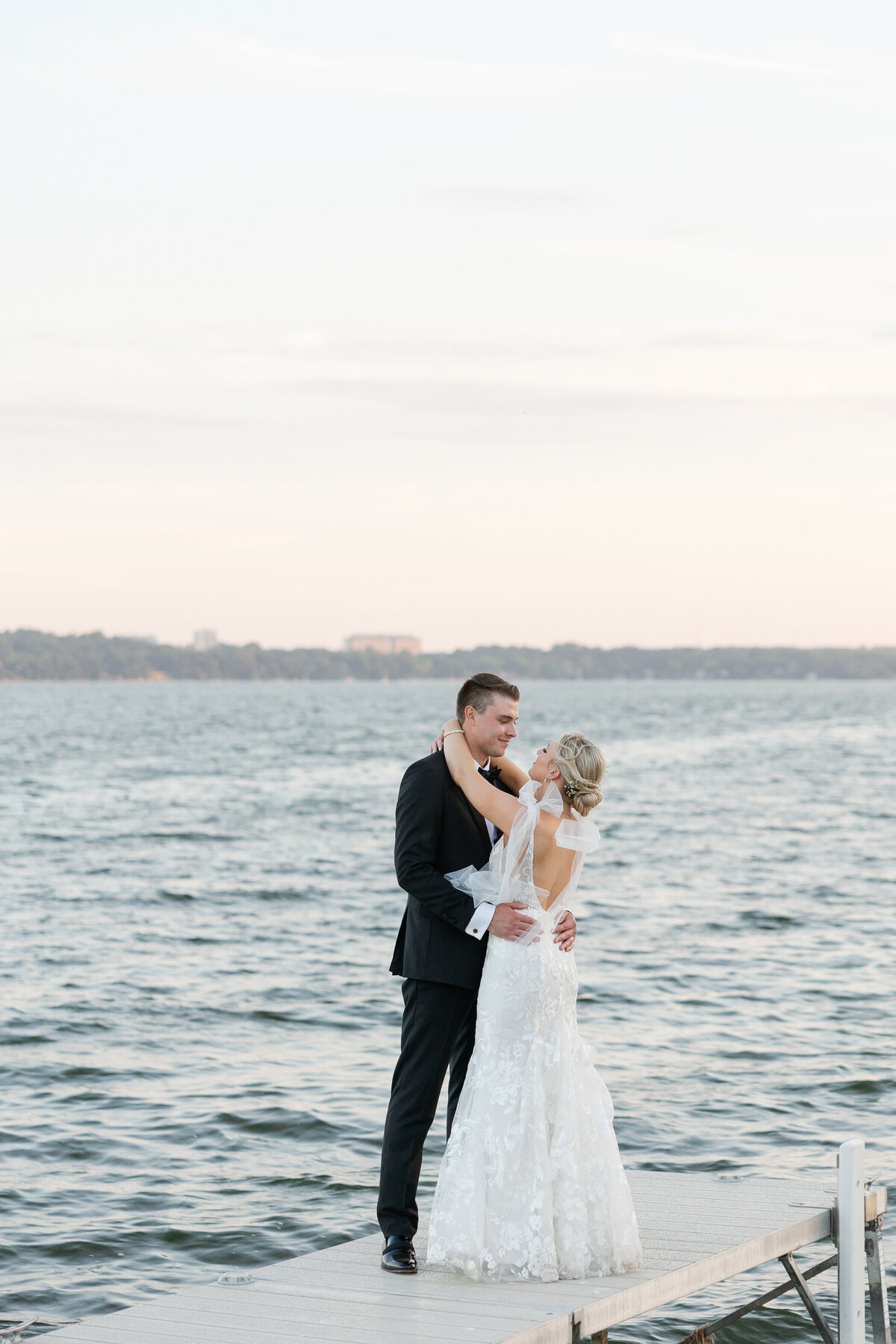 A stunning couple posing along the shoreline at Bishops Bay, showcasing the venue's lush greenery and panoramic water views.