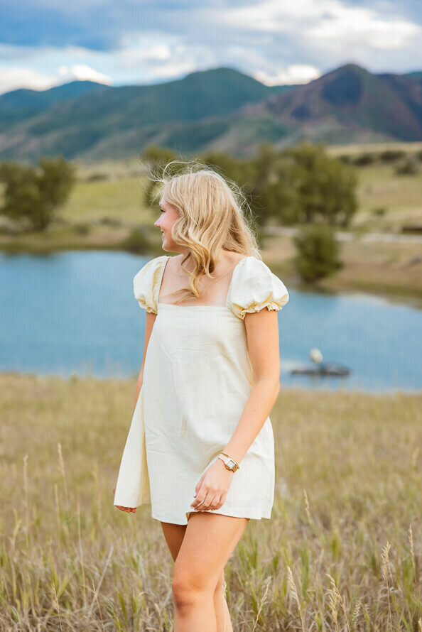 Girl in yellow dress looks over her shoulder at a lake at South Valley Park.