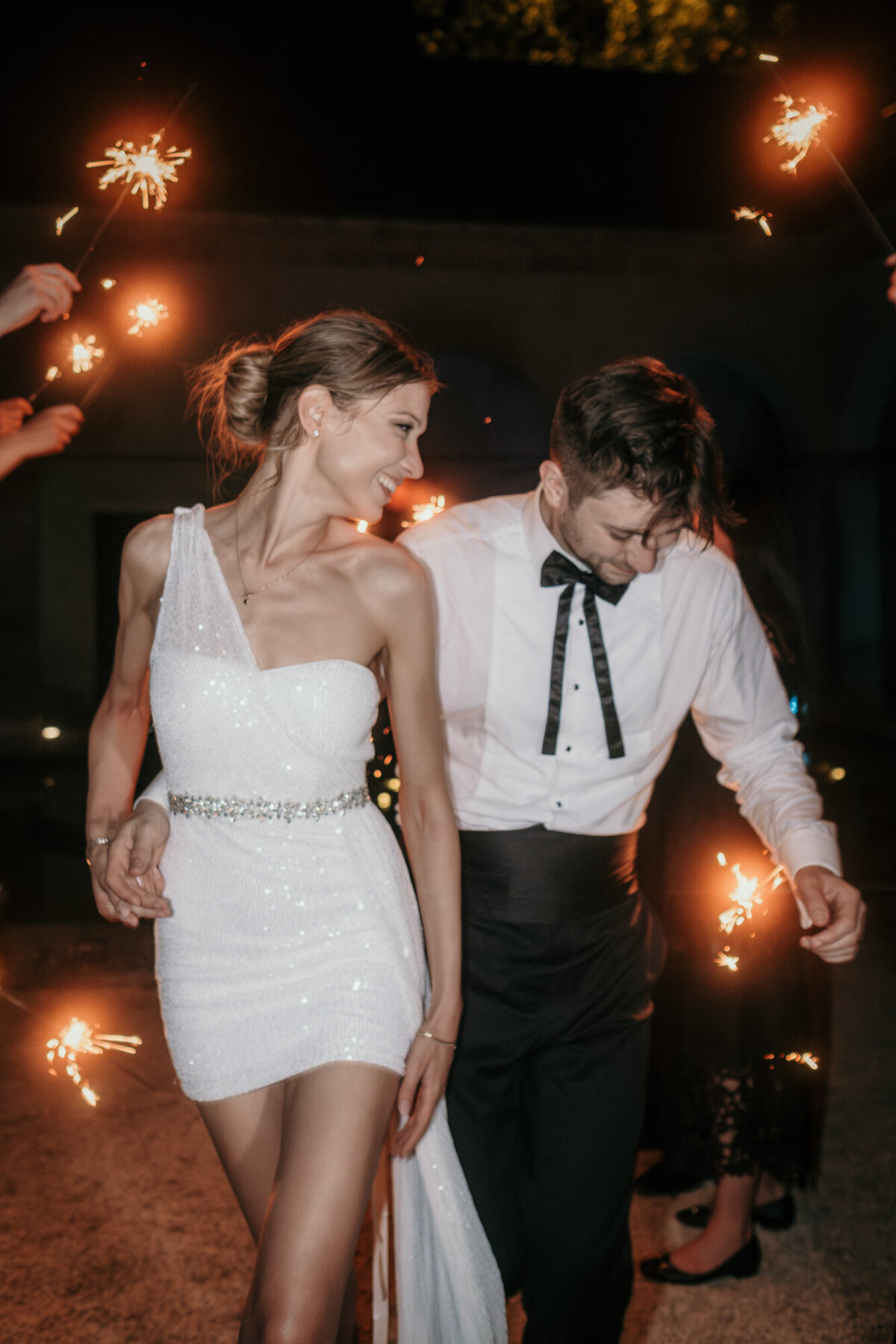 Bride and groom walk happily trough a sparkler trellis.