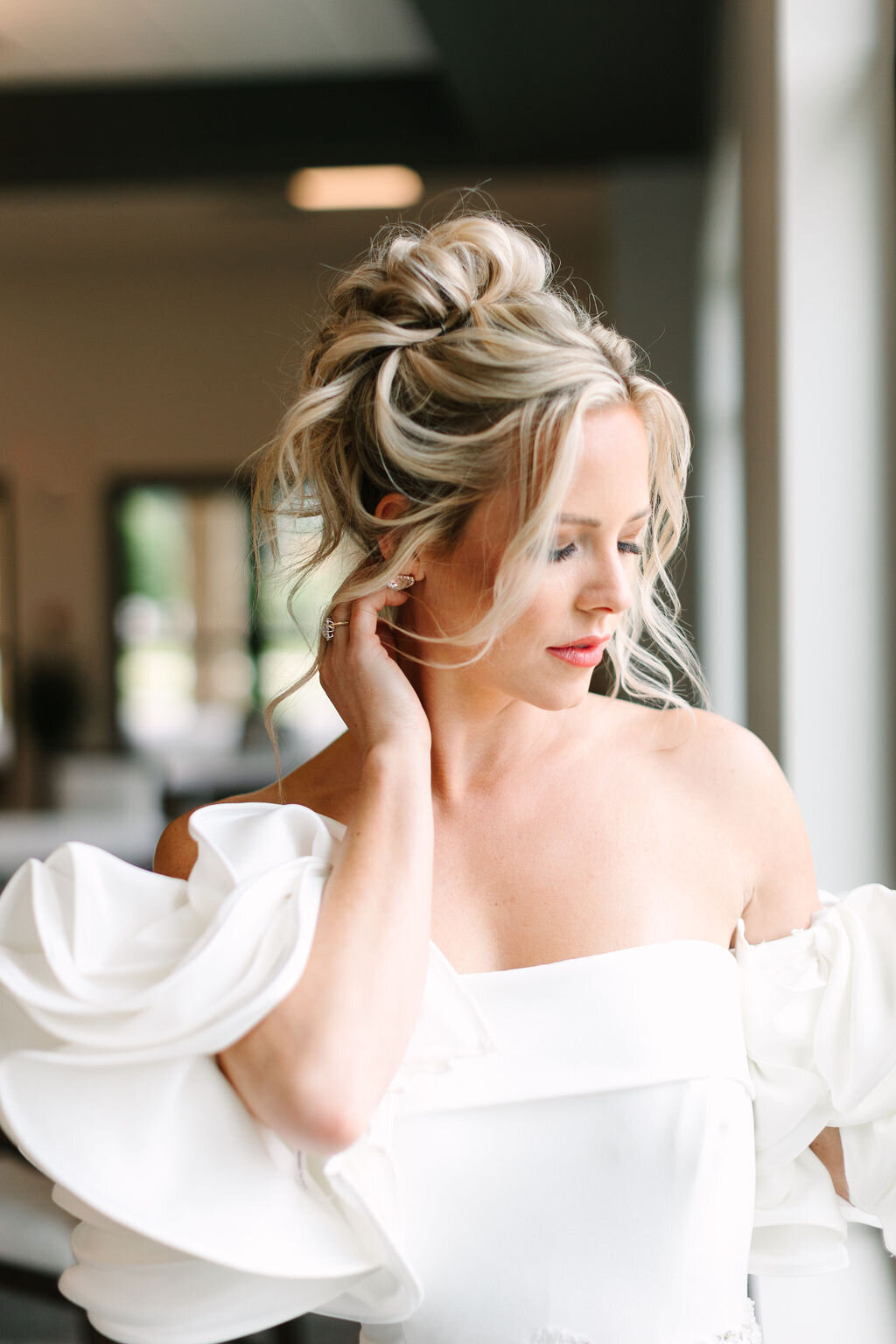 Bridal portrait with a blonde haired bride, wearing a loose high updo. Bride is wearing a goqn from be that queen bridal boutiuque.