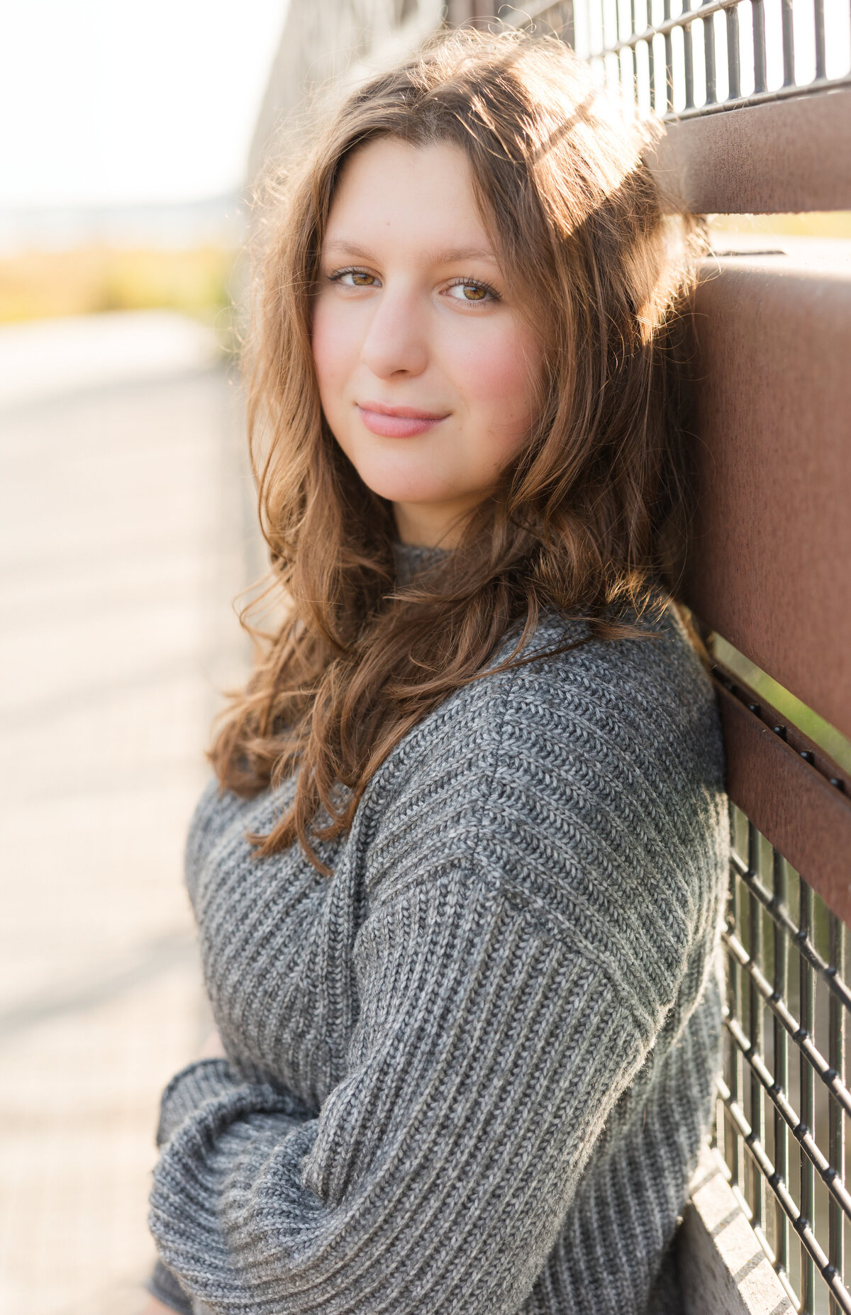 Senior girl leaning along a wall smiling at the camera