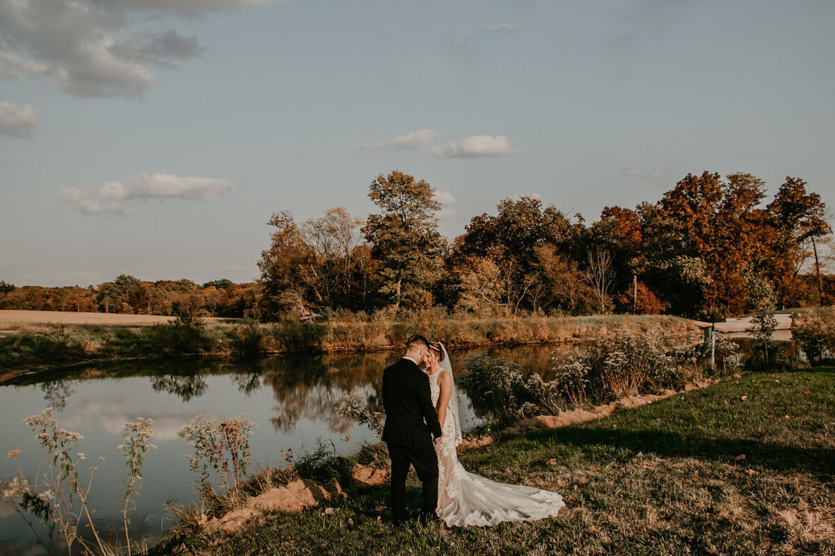 couple-reflection-by-pond-iowa-wedding-whispering-waters-venue-new-london-missouri-storyteller-collective-photo-co