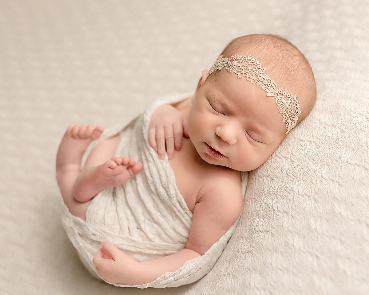 baby girl laying on back with lace headband in pdx studio