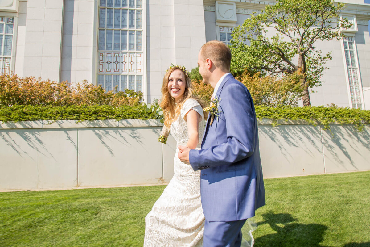 Happy wedding couple walks on side of lds temple