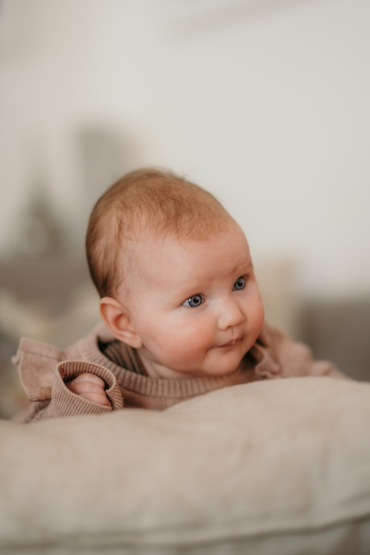 Newborn photography of baby leaning against a pillow.