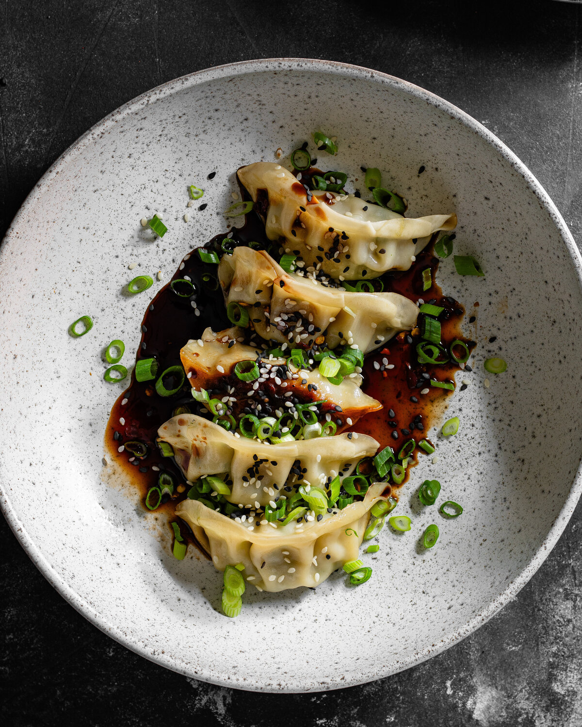 5 Vegetable Gyoza in a bowl with spring onion and soy sauce garnish
