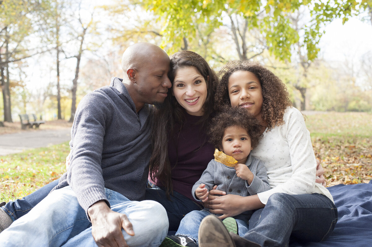 A family of four sitting together with their arms around each other 