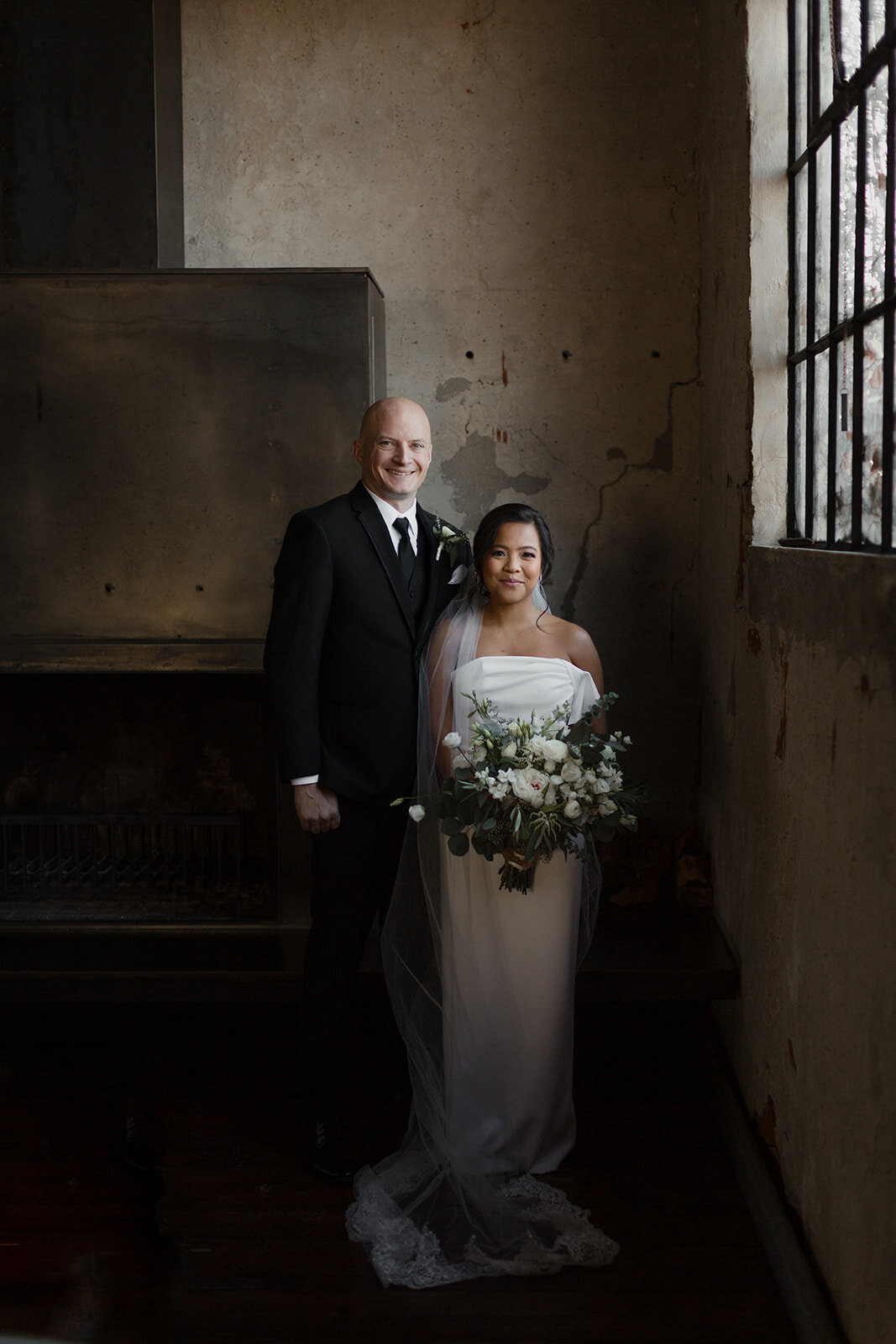 couple posed by window in a moody photo