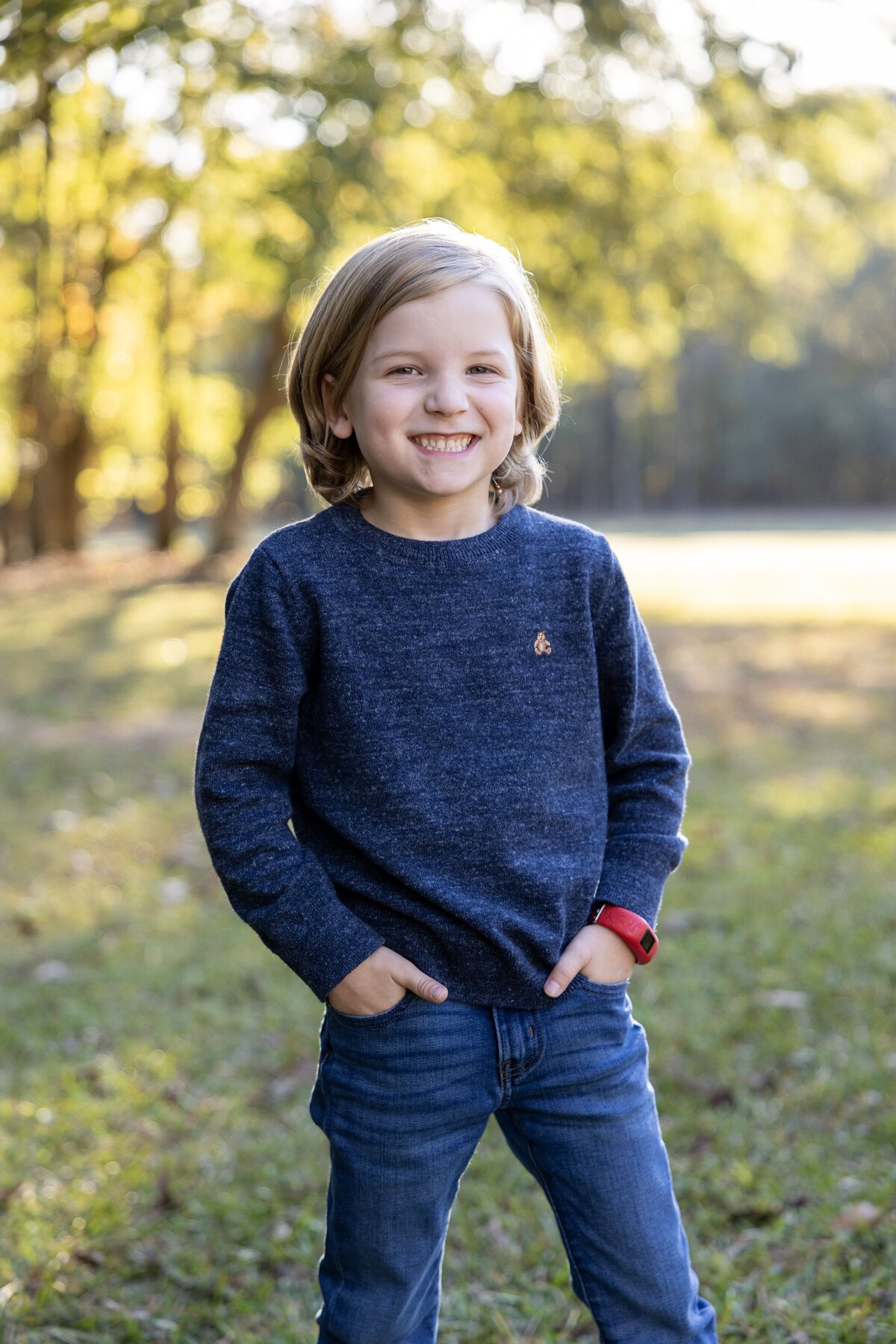 a boy smiling with hands in pockets