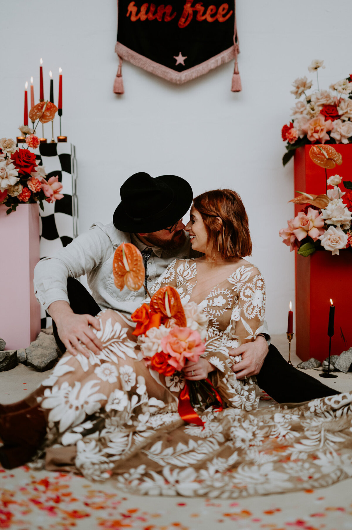 Wedding couple sit on the floor  in front of pink flowers