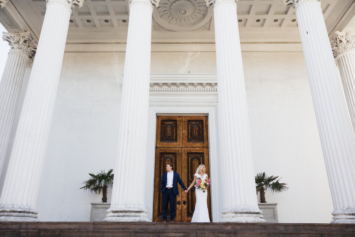 Couple holding hands on their wedding day and looking into the view.