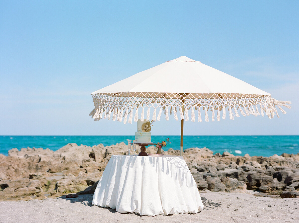 A little umbrella and  table on the beach.