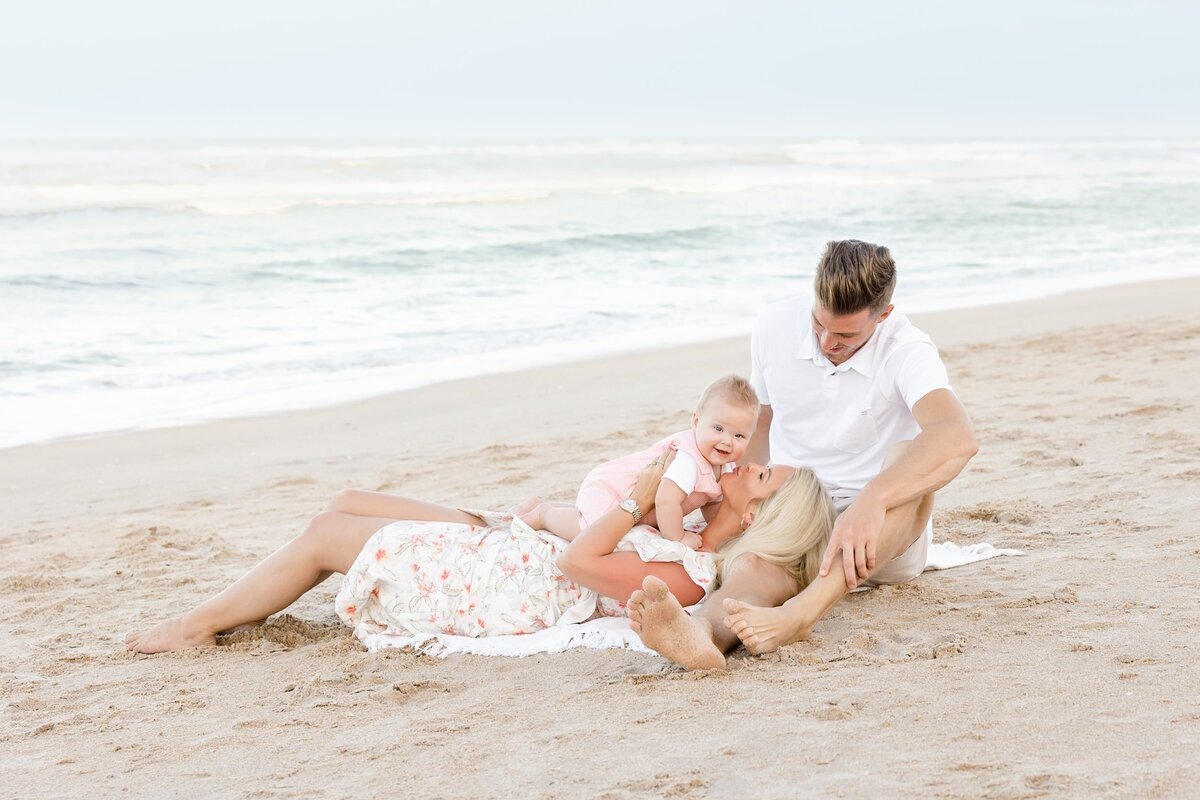 Family laying on blanket at the beach