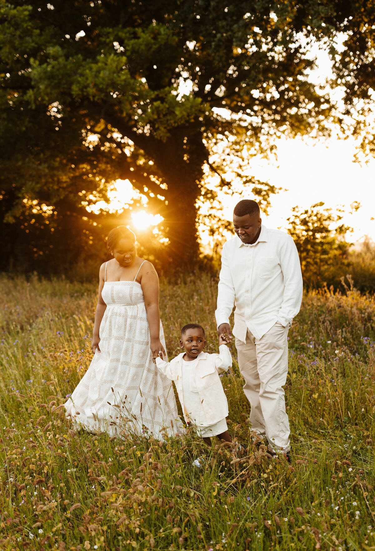 A mother and father walking their son in a christchurch  park while being directed by lucy jane, a canterbury family photographer