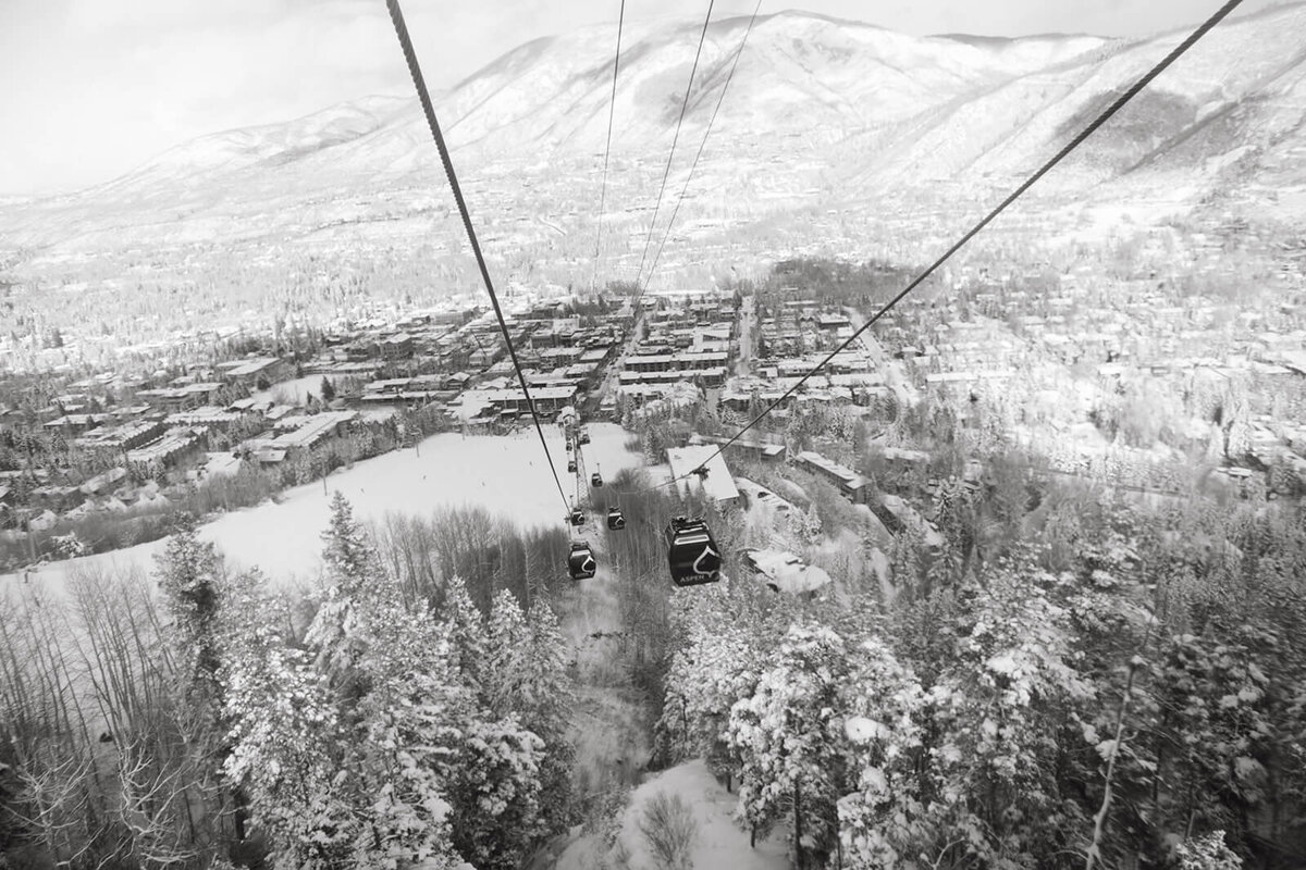 View of ski gondolas surrounded by snow-capped mountains and lush greenery, captured near the St. Regis Aspen wedding venue.