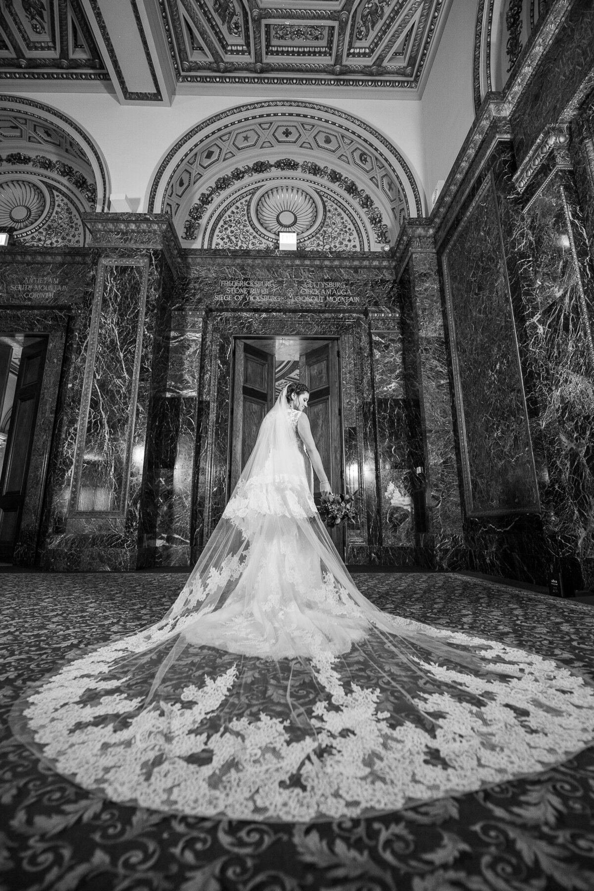 A bride with long veil posing  in Gar Hall at the Chicago Cultural Center