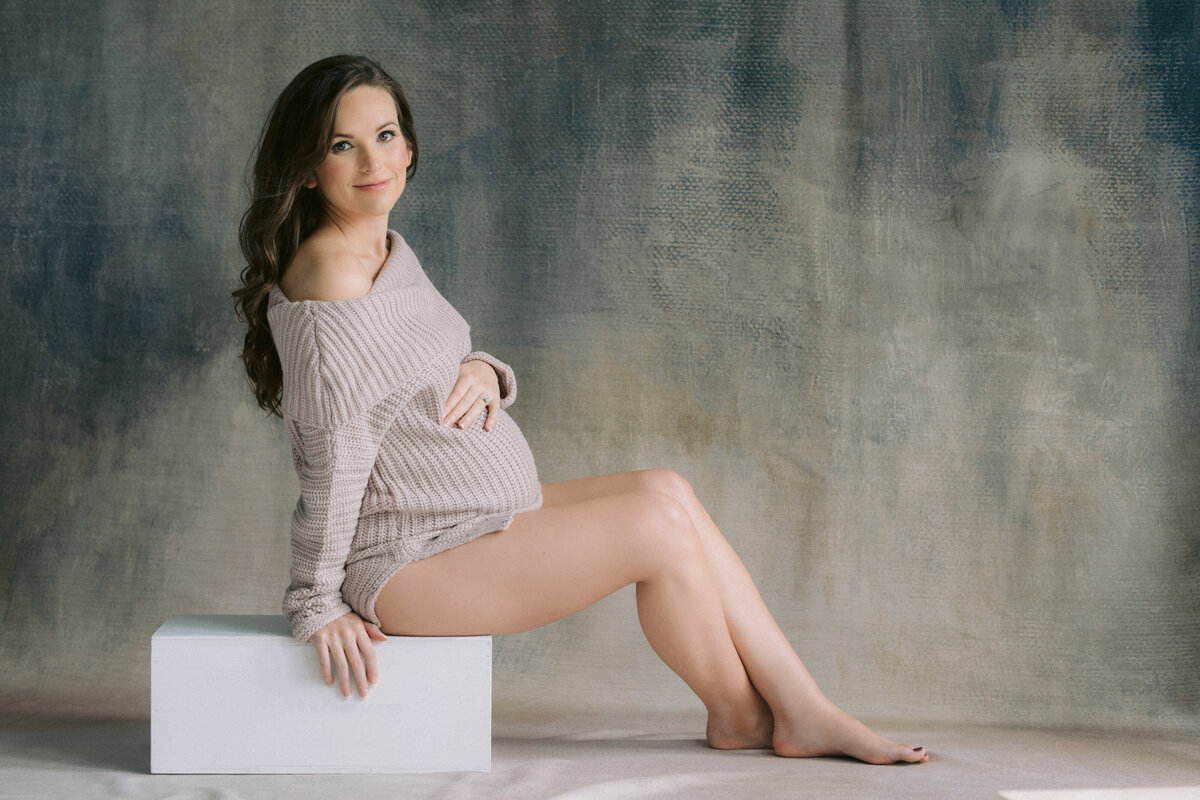 A pregnant person sitting on a small box