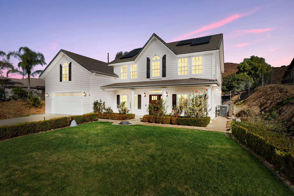 Virtual Twilight front of a white home in Ramona, Ca. Purple twilight skies and lights on in the home.