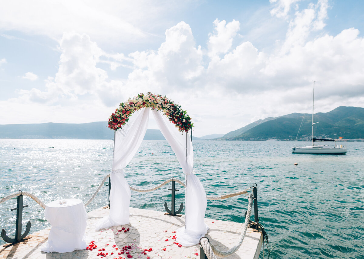 A wedding arch is set at the end of the aisle with panoramic views of the mountains and sea in Greece.