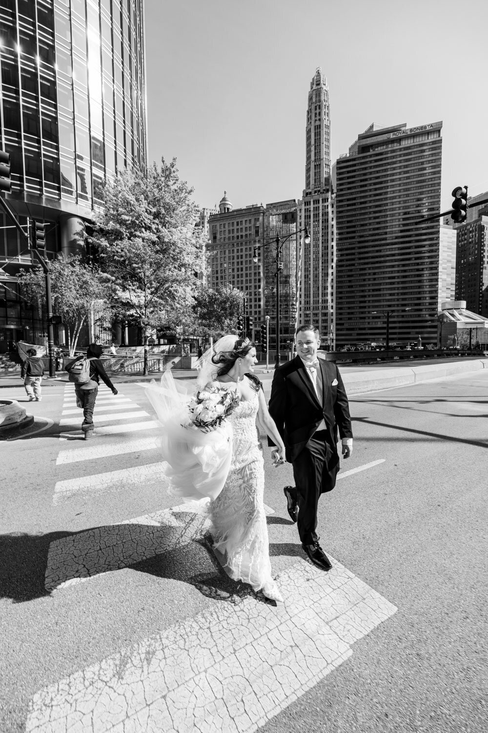 A black and white photo of a bride and groom crossing a street