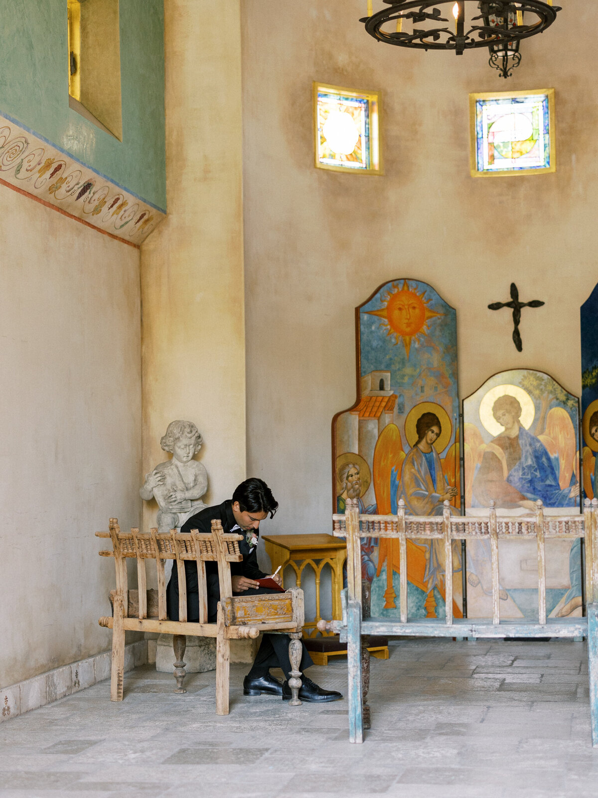 Quiet pre-ceremony moment—groom finds peace and reflection in the Allegretto Vineyard Abbey Chapel, surrounded by sacred art.