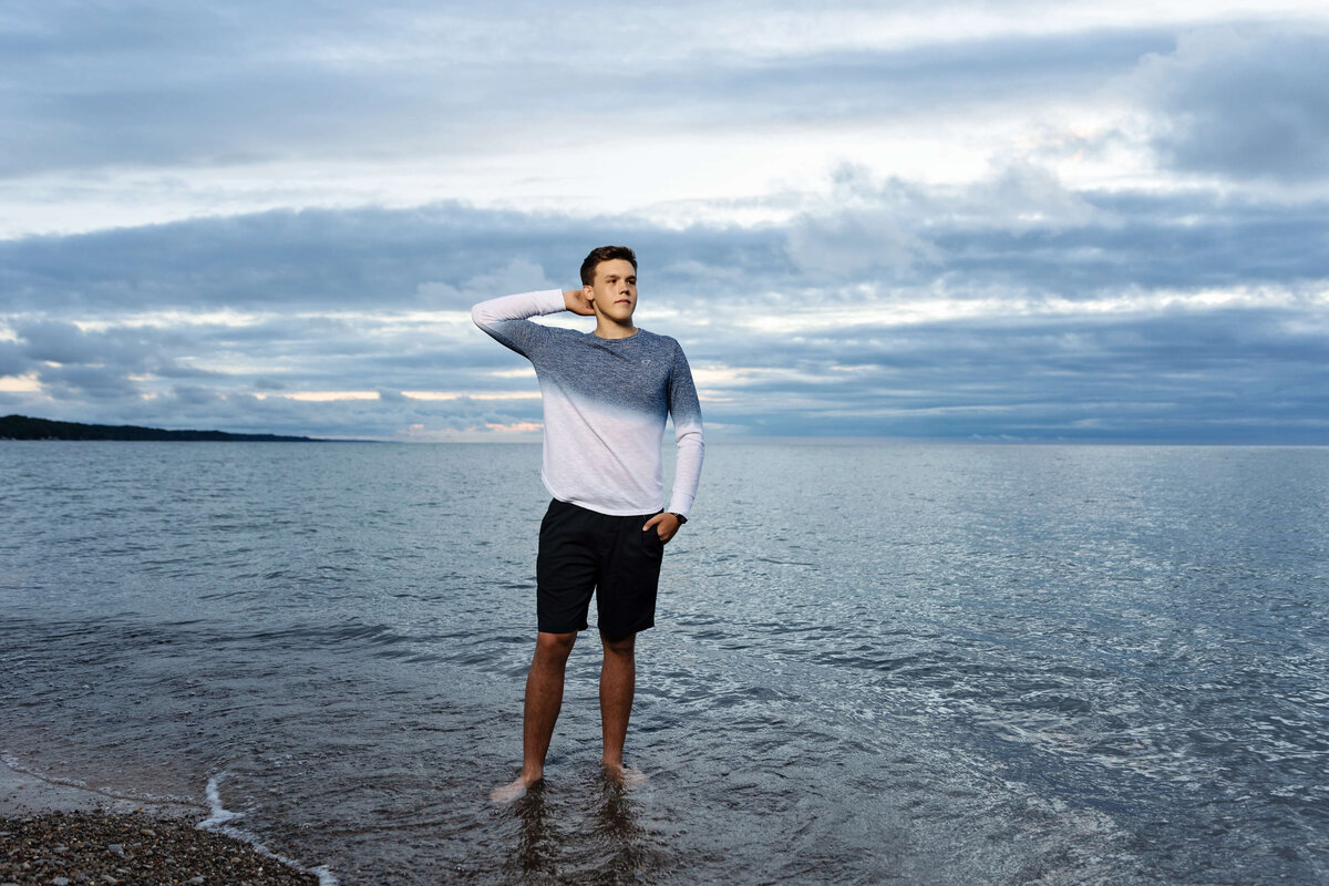 Senior photo of a high school boy looking off to the distance over the water at Presque Isle State park in Erie Pa