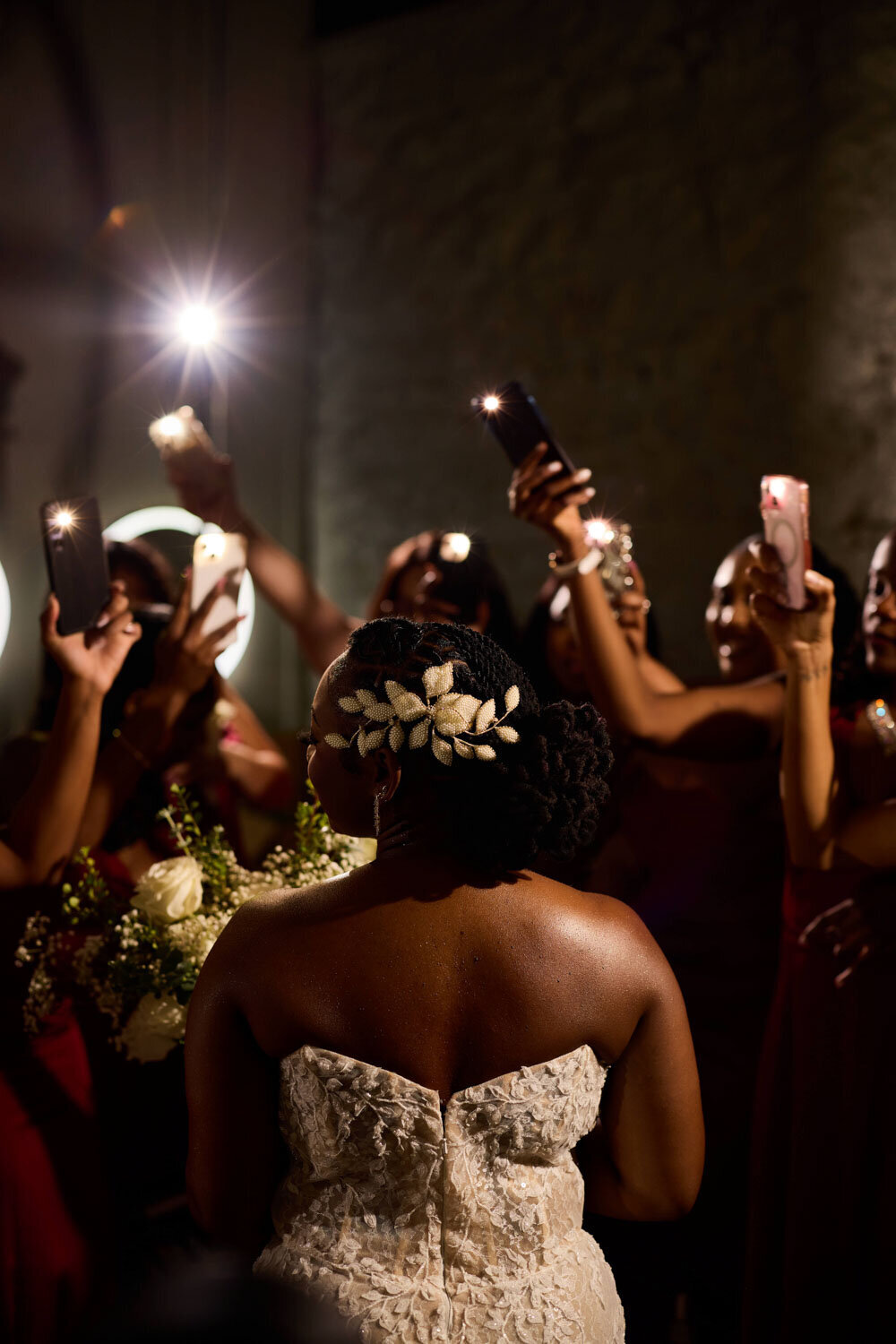 Brides pose while bridesmaids taking a photo of her